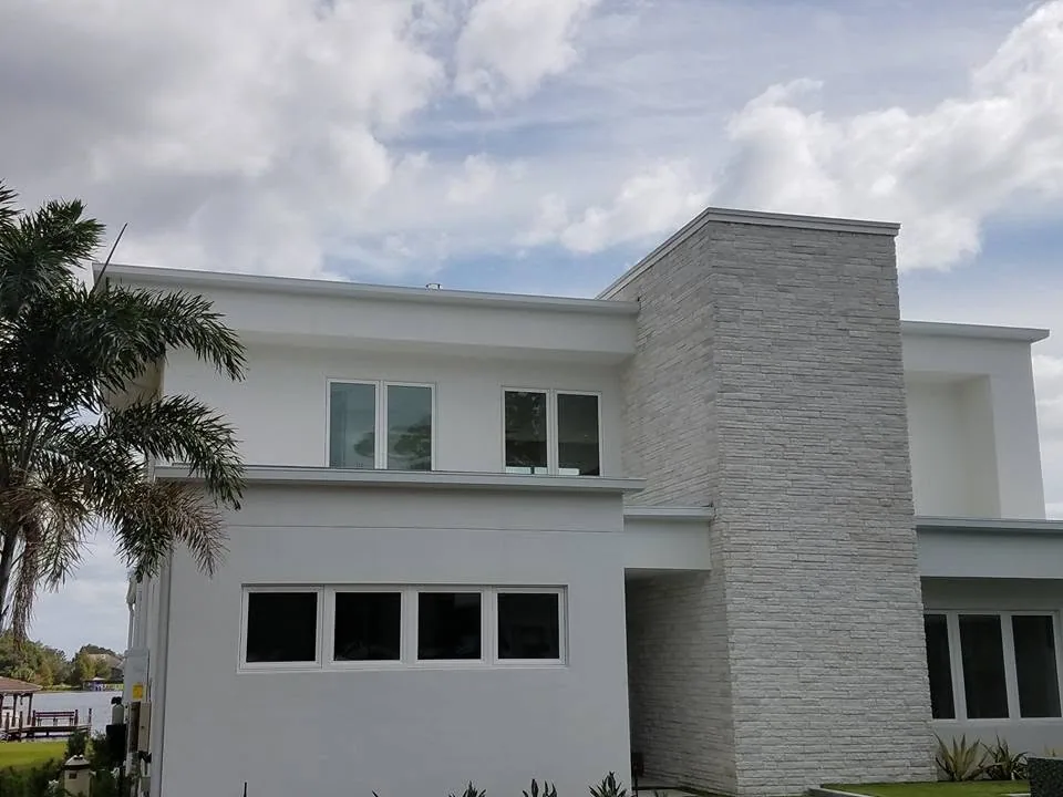 Lakefront flat roof white stucco stacked stone tower box gutters, Sanford